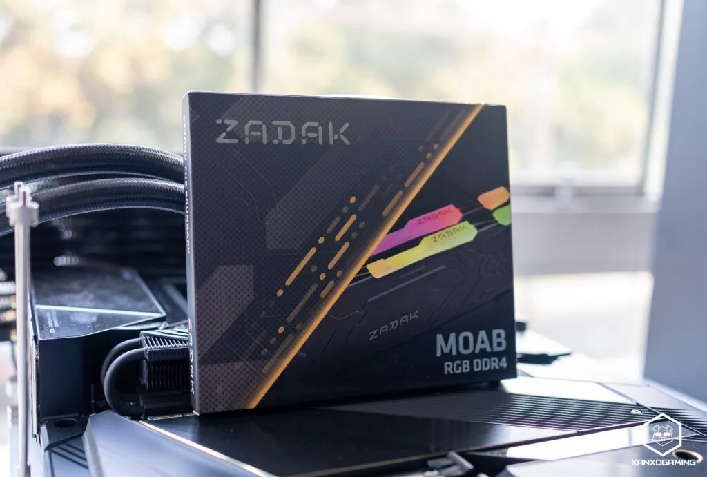 Caja de memoria RAM ZADAK MOAB DDR4, con un diseño colorido y moderno, sobre una superficie negra y brillante.