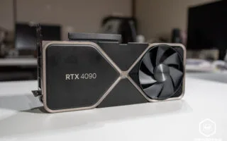 Tarjeta gráfica RTX 4090 con diseño negro y detalles en dorado, con un gran ventilador visible, sobre una superficie blanca.