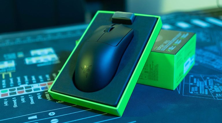 Ratón Razer Viper V3 Pro en su caja, sobre una superficie oscura con gráficos, destacando su diseño negro y detalles verdes.