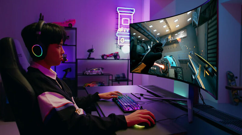 Joven concentrado jugando en un monitor curvo, con auriculares y teclado iluminados, en un ambiente de luz azul y rosa.