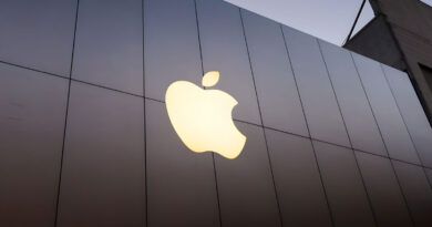 Logo de Apple iluminado contra un fondo de paneles oscuros, destacado con un resplandor suave al atardecer.