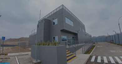 Edificio moderno y gris de un centro de datos, con escaleras y una entrada amplia, rodeado de un entorno árido y montañoso.