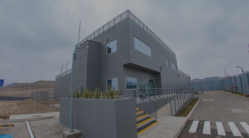Edificio moderno y gris de un centro de datos, con escaleras y una entrada amplia, rodeado de un entorno árido y montañoso.