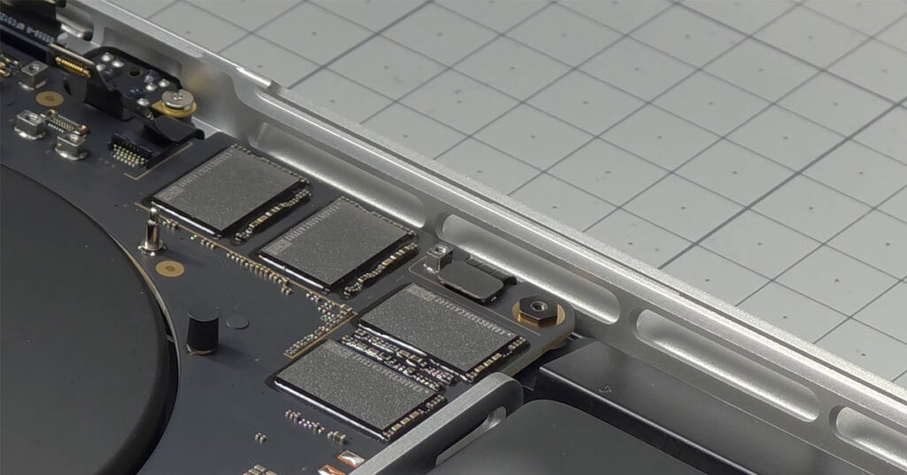 Vista cercana del SSD dentro de un MacBook Pro, mostrando componentes en tonales grises sobre fondo gris claro.