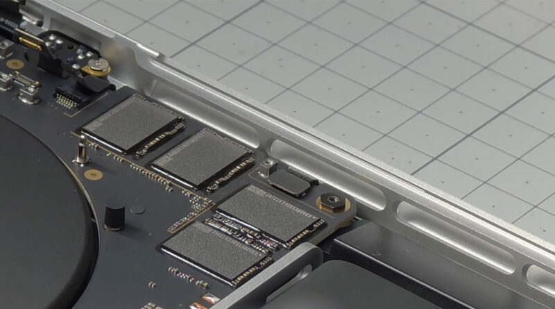 Vista cercana del SSD dentro de un MacBook Pro, mostrando componentes en tonales grises sobre fondo gris claro.