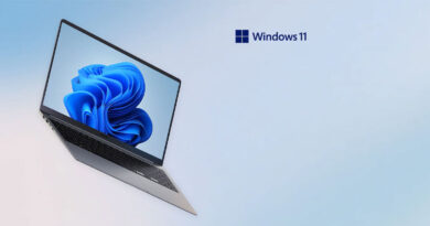 Portátil moderno con pantalla que muestra el logo de Windows 11, sobre un fondo suave en tonos azules.
