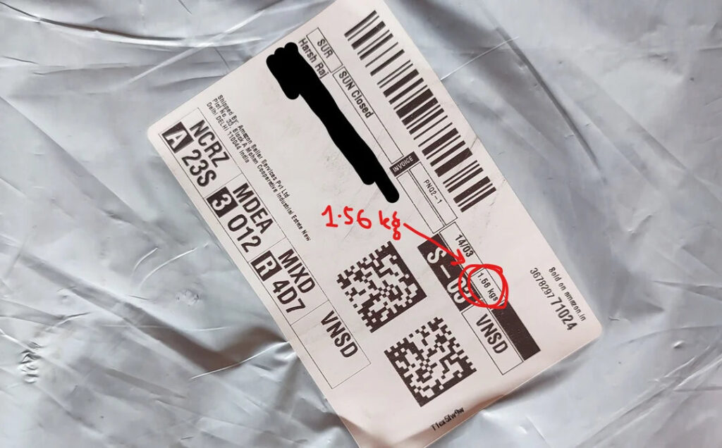 Etiqueta de envío con código de barras, detalles de envío y anotaciones manuscritas en tinta roja sobre un fondo gris.