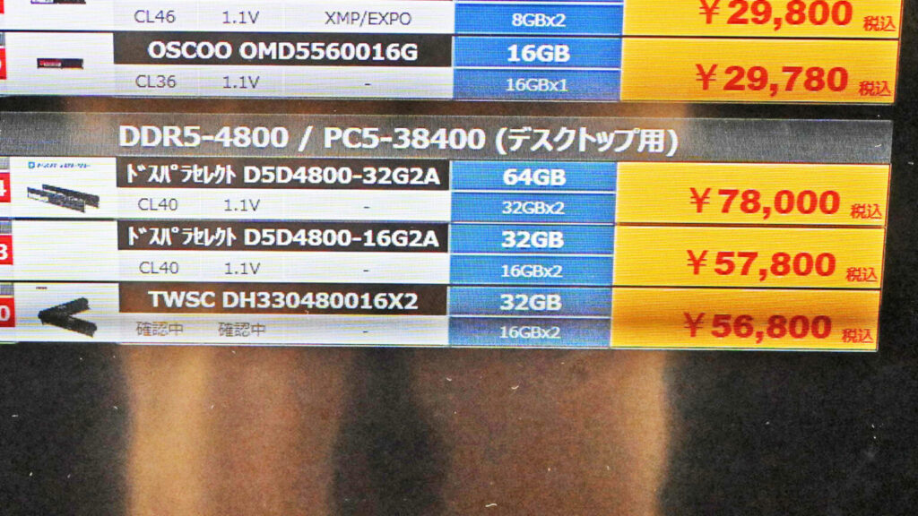 Cartel informativo con precios de kits DDR5: 64GB a ¥78,000 y 32GB a ¥57,800 y ¥56,800, sobre fondo blanco y negro.