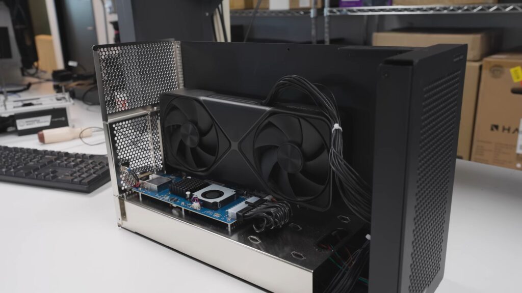 Caja de eGPU con un sistema de refrigeración y dos ventiladores, conectada a una placa base con un diseño limpio y moderno.