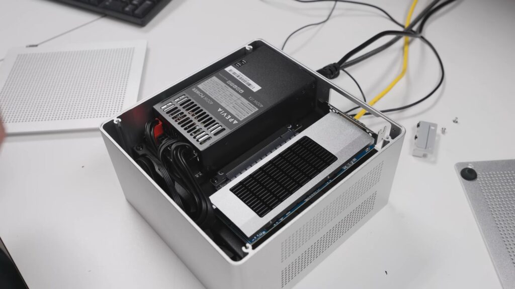 Unidad de procesamiento gráfico RTX 5090 montada en un gabinete blanco, con cables conectados a la fuente de alimentación y placa madre.