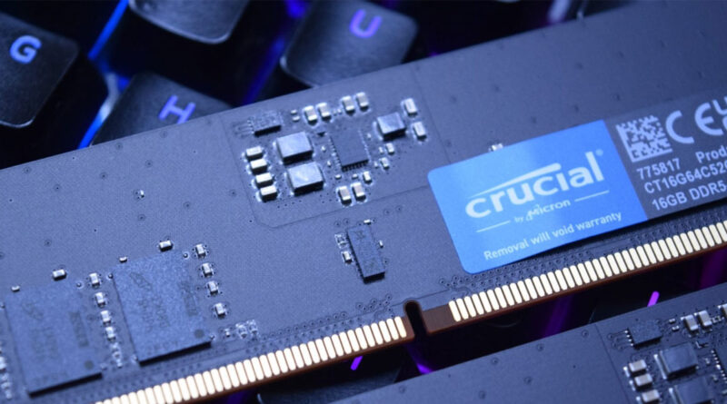 Módulo de memoria RAM DDR5 de 16 GB Crucial, con detalles de circuitos y una etiqueta azul sobre fondo oscuro y luminiscente.