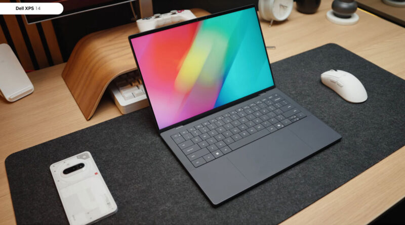 Laptop Dell XPS 14 sobre una mesa de madera, con pantalla colorida, teclado plano y un ratón blanco a su lado. Fondo minimalista.