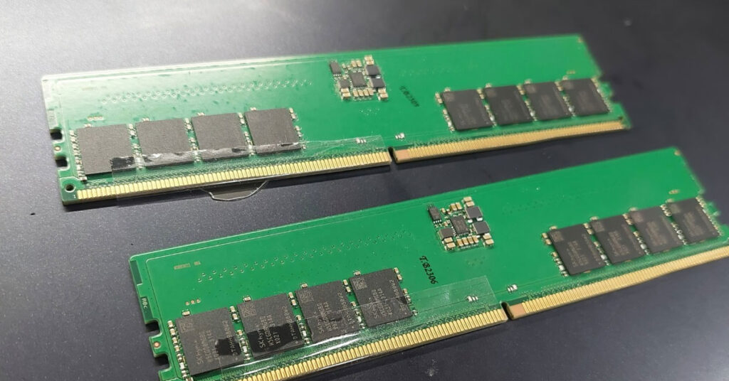 Dos módulos de memoria RAM, con PCB verde y chips de memoria oscura, colocados en una superficie gris oscura, muestra el diseño interno.