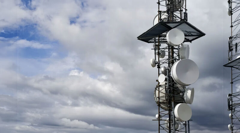 Antenas de telecomunicaciones en una torre, con un cielo nublado y azul de fondo, resaltando la infraestructura de conectividad.