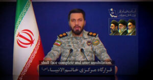 Militar con uniforme en un podio, con bandera de Irán de fondo y retratos de líderes en la pared. Subtítulos en inglés.