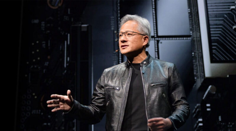 Jensen Huang, con chaqueta de cuero y gafas, habla en un escenario con fondo de circuitos y componentes tecnológicos.