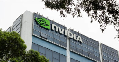 Logotipo verde de NVIDIA en un edificio moderno de cristal, con vegetación en primer plano y un cielo nublado al fondo.