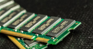 Módulos de memoria RAM en ángulo, con circuitos impresos en verde y componentes en negro, sobre fondo oscuro y texturizado.