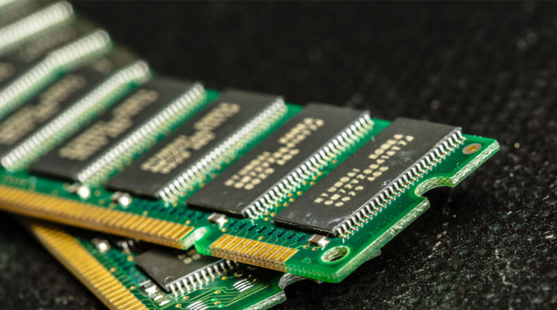 Módulos de memoria RAM en ángulo, con circuitos impresos en verde y componentes en negro, sobre fondo oscuro y texturizado.