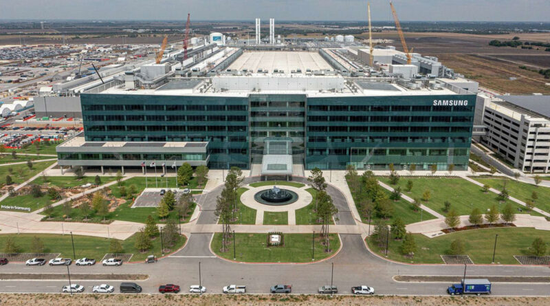 Fábrica de Samsung en Taylor, EE.UU., con un edificio moderno y amplio, árboles alineados y vehículos en el estacionamiento.