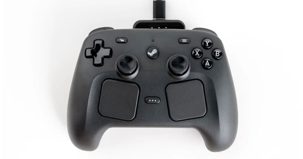 Controlador negro con joysticks, botones y superficie texturizada, conectado a un puerto USB en una base. Fondo blanco.