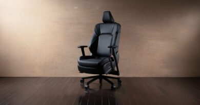 Silla gaming negra con diseño ergonómico, reposabrazos ajustables y base giratoria, sobre un fondo marrón claro.