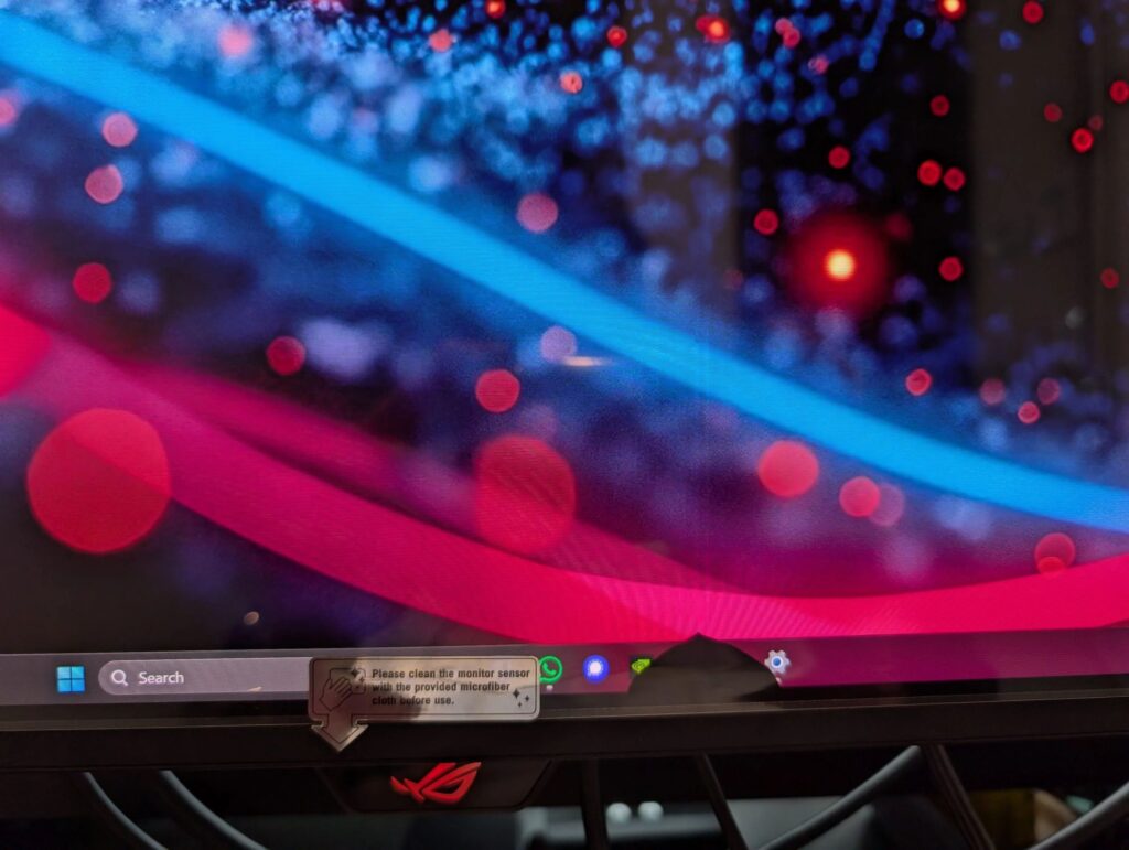 Pantalla de monitor ASUS ROG con errores visibles; se observa una marca de golpe y colores vibrantes en el fondo.