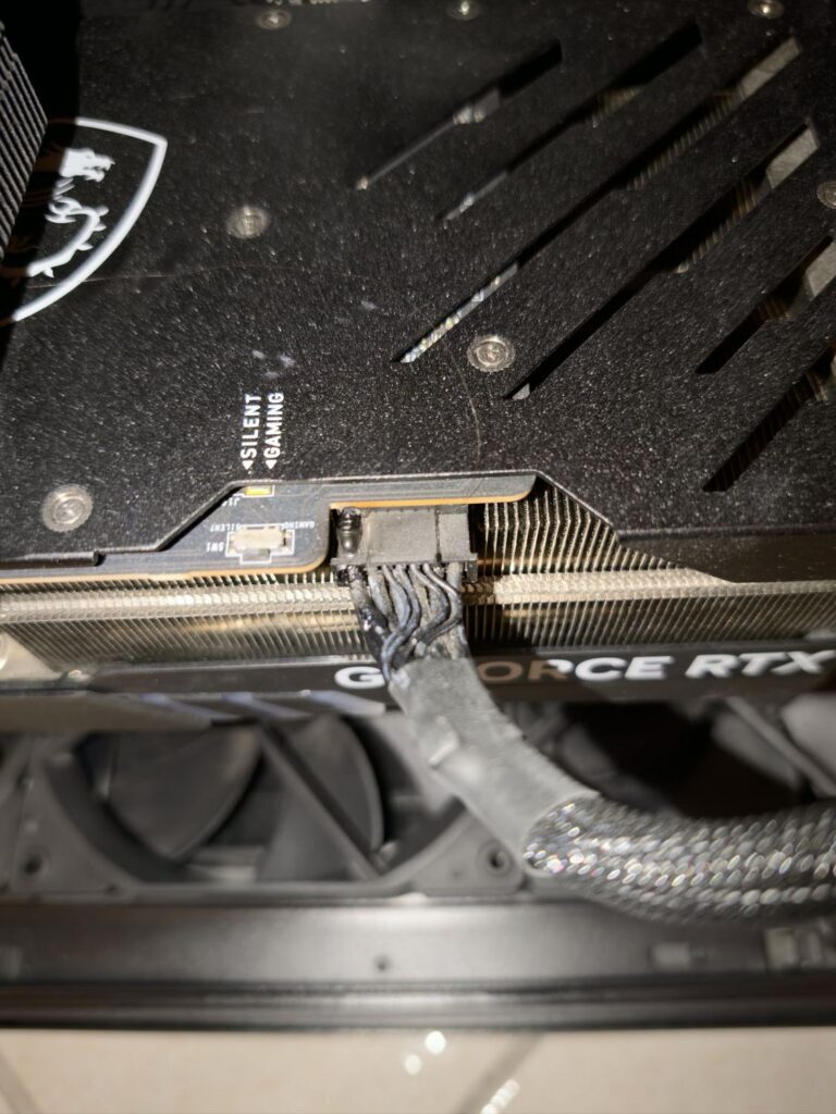 Conector de una tarjeta gráfica MSI RTX 4090 con cables quemados, mostrando signos visibles de daño por incendio. Fondo oscuro.