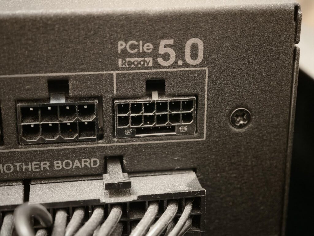 Conectores PCIe 5.0 en la parte trasera de una tarjeta gráfica, con múltiples pines y cables organizados en negro.
