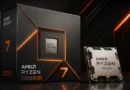 Caja del procesador AMD Ryzen 7 7700X3D destacando sus gráficos en negro y naranja, con el chip visible a la derecha sobre una superficie brillante.