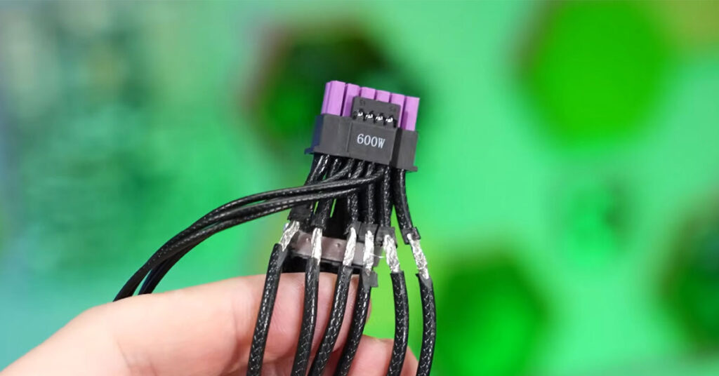 Conector de cable de alimentación ASUS ROG Equalizer, negro con terminaciones moradas y múltiples hilos, sostenido por una mano, fondo verde.