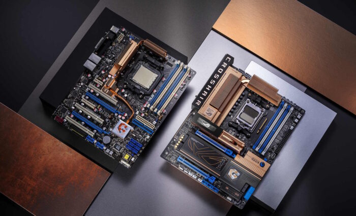 Placas base ROG Crosshair en tonos negro y azul, con disipadores de calor dorados, sobre un fondo de superficies metálicas en tonos cobre y plata.