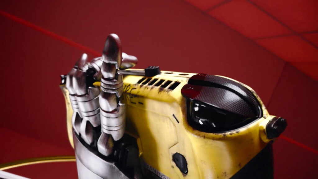 Controlador amarillo con detalles metálicos y un diseño futurista, apoyado sobre una superficie roja, destacando su estética cyberpunk.