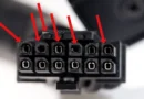 Conector de alimentación con múltiples pines, algunos de los cuales presentan daños visibles, resaltados con flechas rojas.