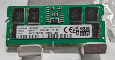 Módulo de memoria DDR5 SO-DIMM con chips de plástico, etiqueta blanca y verde, texto en negro, varios chips oscuros a lo largo.