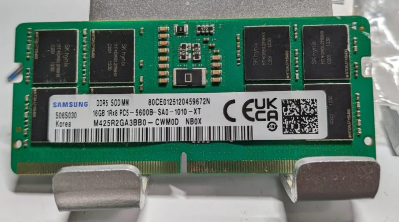 Módulo de memoria DDR5 SO-DIMM con chips de plástico, etiqueta blanca y verde, texto en negro, varios chips oscuros a lo largo.