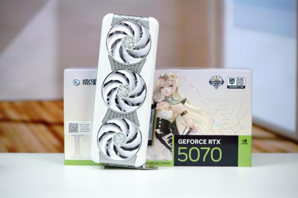 Tarjeta gráfica RTX 5070 LUNA OC en color blanco con tres ventiladores y caja decorada con un personaje femenino, fondo difuso.