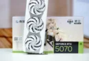 Tarjeta gráfica GeForce RTX 5070 en primer plano, con un diseño blanco y ventiladores circulares, frente a su caja decorada.
