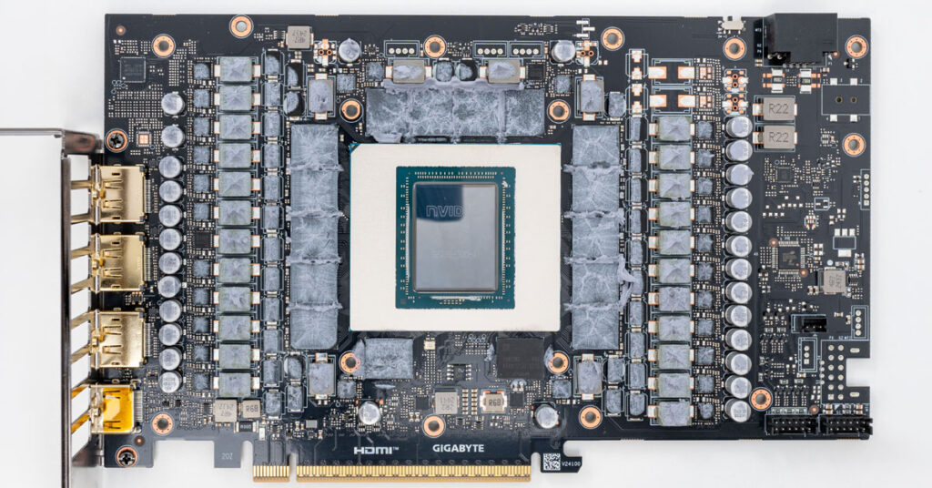 Placa de vídeo GIGABYTE con GPU en el centro, rodeada de circuitos y resistores, en tono negro y gris, con conectores en un lado.