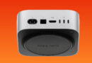 Mac mini en fondo naranja, vista superior con puertos eléctricos, HDMI y Thunderbolt, diseño compacto y moderno.