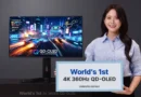 Una mujer sostiene un cartel que anuncia el primer panel QD-OLED 4K 360Hz, mientras se muestra un monitor con gráficos de carreras brillantes.