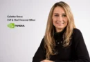 Colette Kress, CFO de NVIDIA, sonríe frente a un fondo blanco, luciendo un suéter negro y con el logo de NVIDIA a la izquierda.