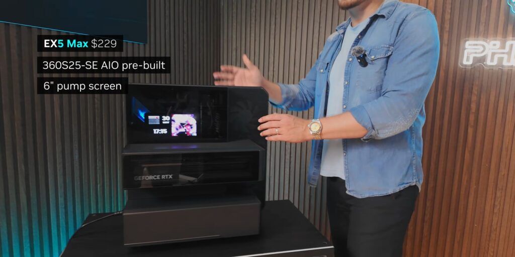 Un hombre presenta un gabinete de computadora con pantalla de 6" y GPU GeForce RTX en un ambiente moderno, con fondo de paneles.