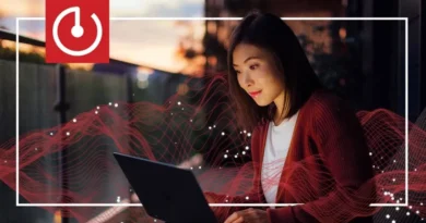 Mujer usando una laptop al atardecer, con ondas rojas de energía alrededor y un logotipo de encendido en la esquina superior izquierda.
