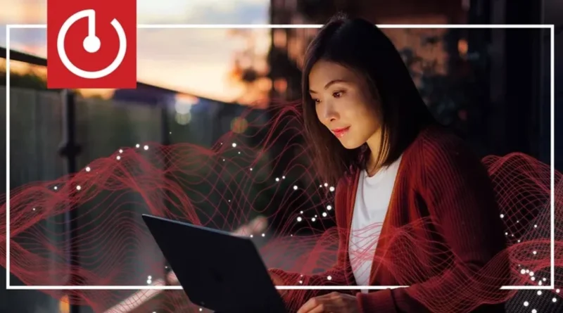 Mujer usando una laptop al atardecer, con ondas rojas de energía alrededor y un logotipo de encendido en la esquina superior izquierda.