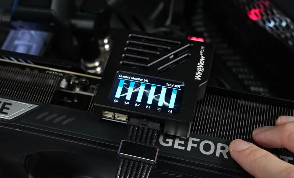Dispositivo WireView PRO con pantalla que muestra datos de corriente, colocado sobre una tarjeta gráfica, en un entorno de hardware gamer.