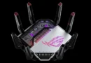 Router de ASUS con diseño hexagonal, antenas en negro y detalles en púrpura, incluida la logo ROG iluminado en la parte superior.