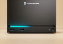 Consola de videojuegos Steam Machine en tonos oscuros, con puertos USB y una luz azul iluminando la parte frontal.