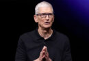 Tim Cook, director de Apple, con polo negro y gafas, gesticulando mientras habla frente a un fondo oscuro y luces moradas.