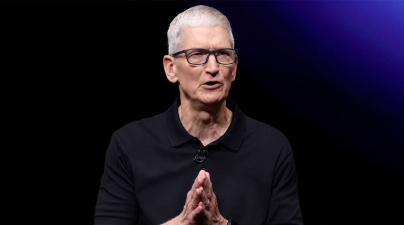 Tim Cook, director de Apple, con polo negro y gafas, gesticulando mientras habla frente a un fondo oscuro y luces moradas.